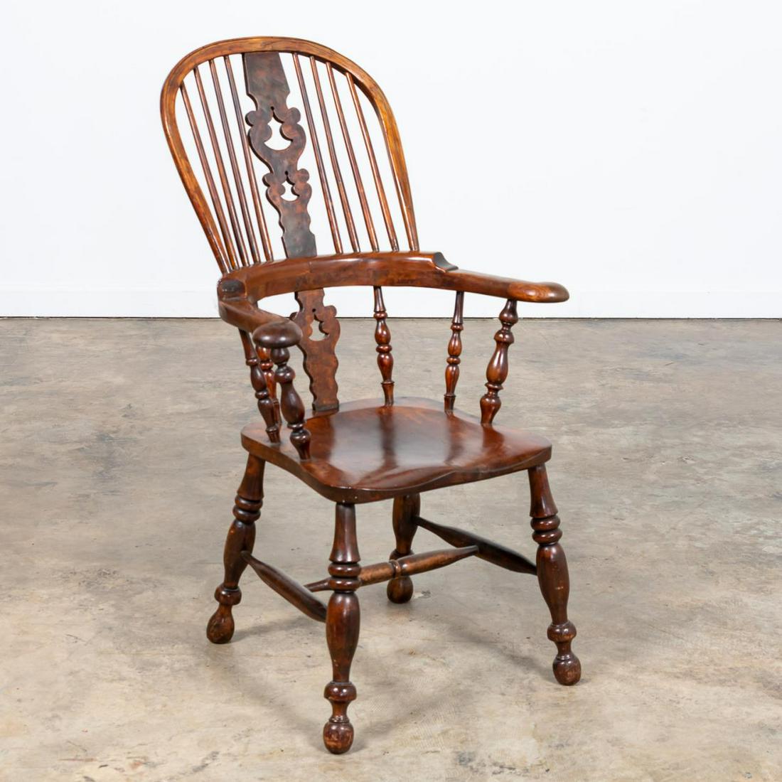 19TH C. ENGLISH WINDSOR ARMCHAIR: English, 19th century. Carved wooden Windsor armchair having a pierced splat, saddle seat, and rising on turned legs with stretcher. Inscriptions to the underside. Approx. h. 43.75", w. 25.25", d. 24"