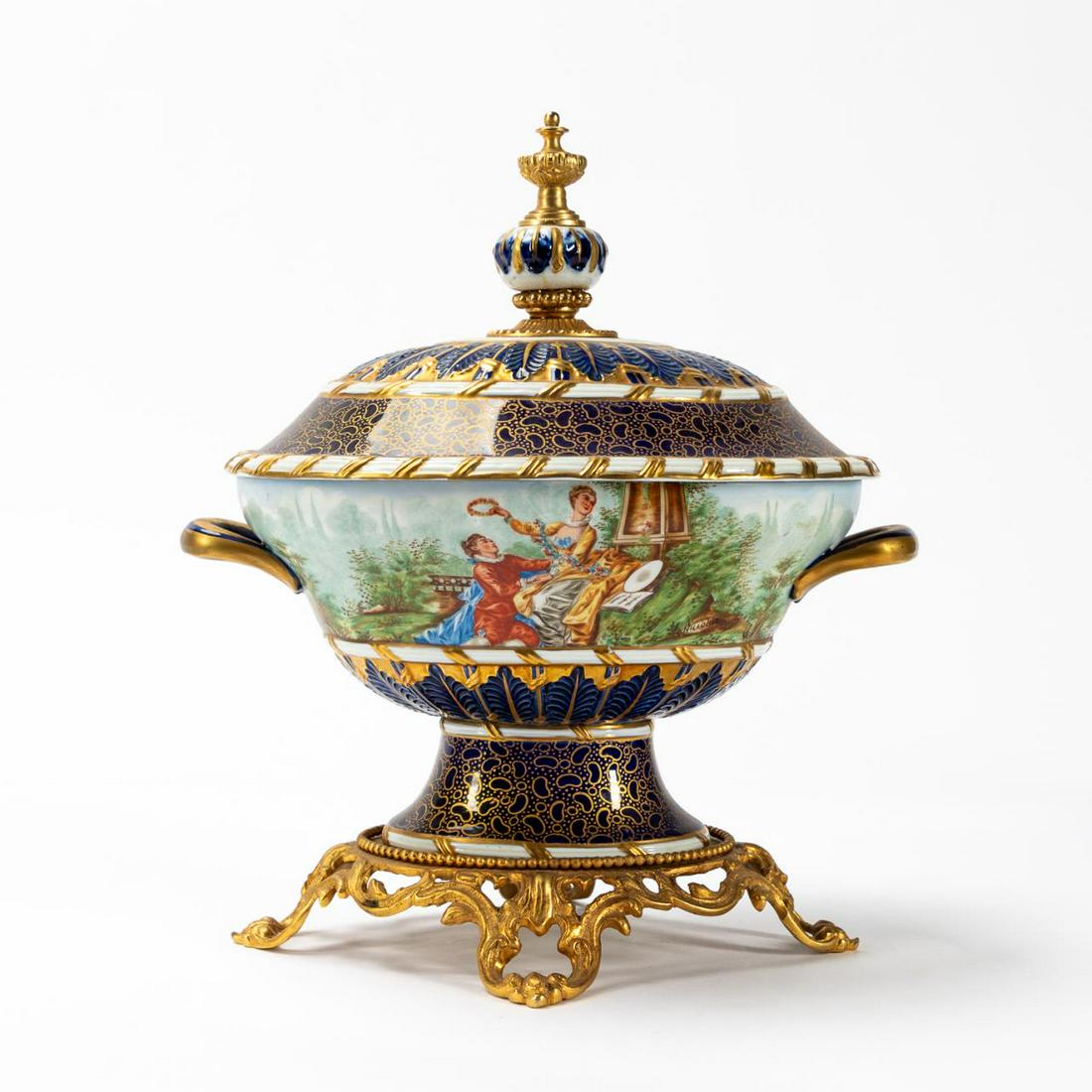 GIULIA MANGANI SEVRES STYLE PORCELAIN TUREEN: Guilia Mangani (Italian, founded 1950), last half 20th century. Oval lidded porcleian tureen in the manner of Sevres, having a cobalt blue ground with gilt accents, the body decorated with a courting 
