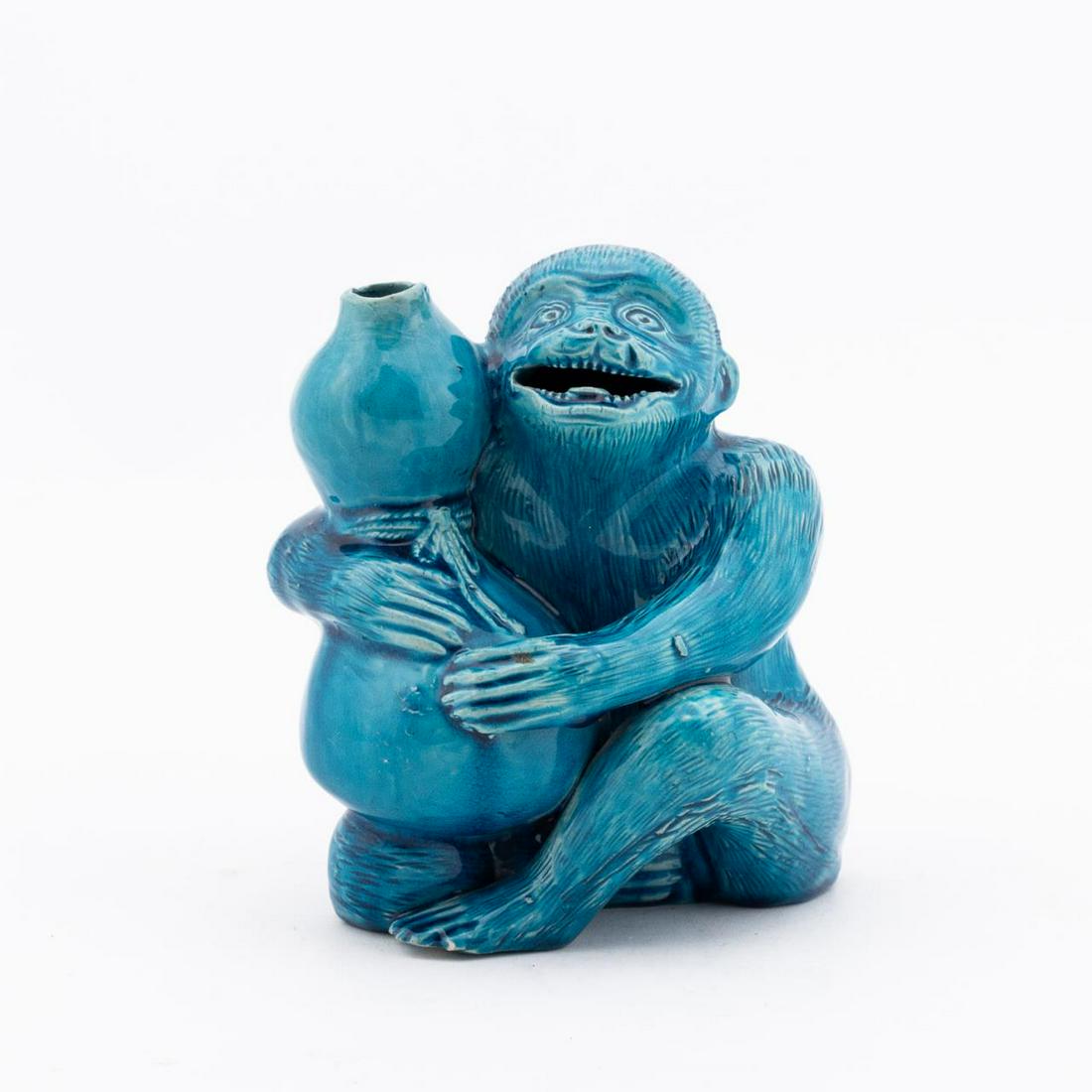 TURQUOISE GLAZE MONKEY HOLDING DOUBLE GOURD VASE: Chinese. Peacock-blue glaze seated monkey figurine holding a double gourd. Apparently unmarked. Approx. h. 6.25".