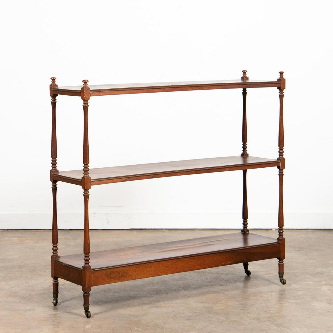 19TH C. ENGLISH THREE-TIER ROSEWOOD TROLLEY: English, 19th century. Three-tier rosewood trolley or etagere, having turned supports and legs with casters. Unmarked. Approx. h. 39", w. 42", d. 11.5".