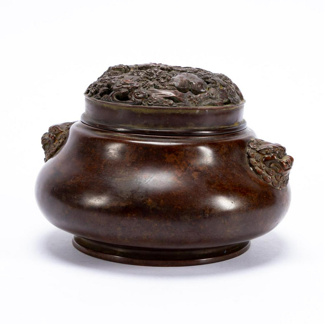 CHINESE GUARDIAN LION PIERCED LID BRONZE CENSER: Chinese. Footed patinated cast bronze censer, having a pierced lid decorated with Buddhist guardian lions, and lion mask handles. Cast Qianlong type seal mark to the underside. Approx. h. 4.5", dia. 7