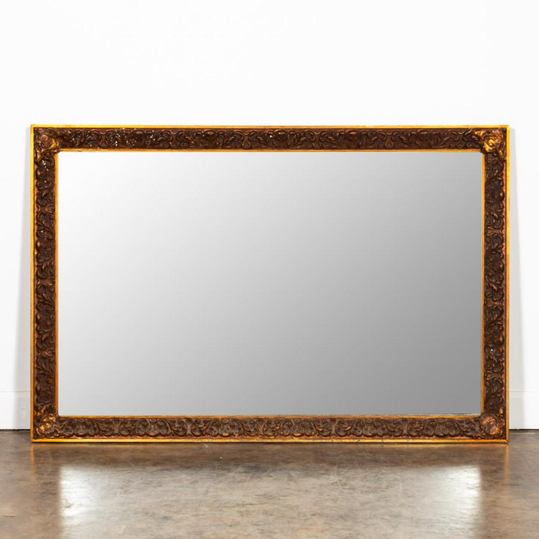 JA OLSON & CO, GOLD FOLIATE WALL MIRROR: JA Olson (American/Mississippi, 20th century). Cast compo foliate decorated and gold painted mirror with cast shield form corners. Labeled verso. Approx. 53.5" x 35.5"