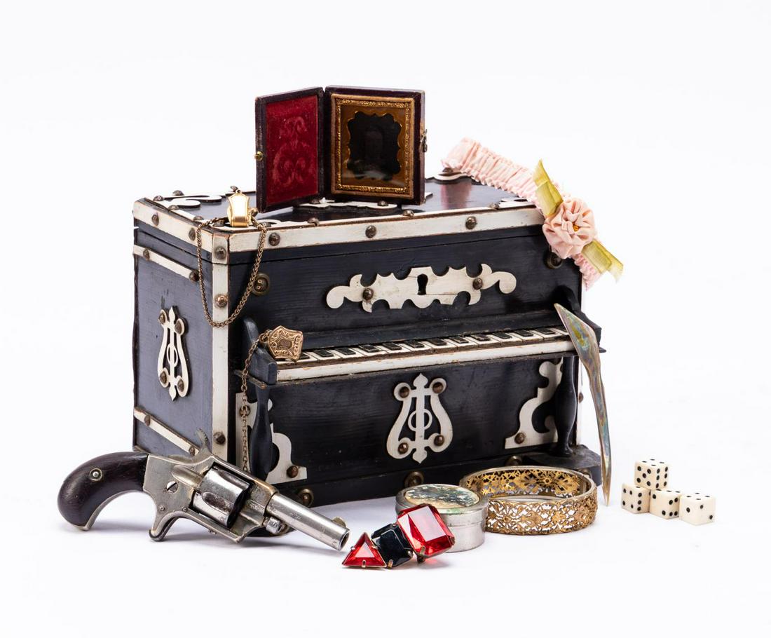 EBONIZED PIANO FORM BOX WITH PROPS & MINI REVOLVER: Group of theater prop items in decorative wooden piano box with fitted mini revolver shelf. Comprising of a vintage North American style mini revolver (marked 230 under grip), pink garter, small dague