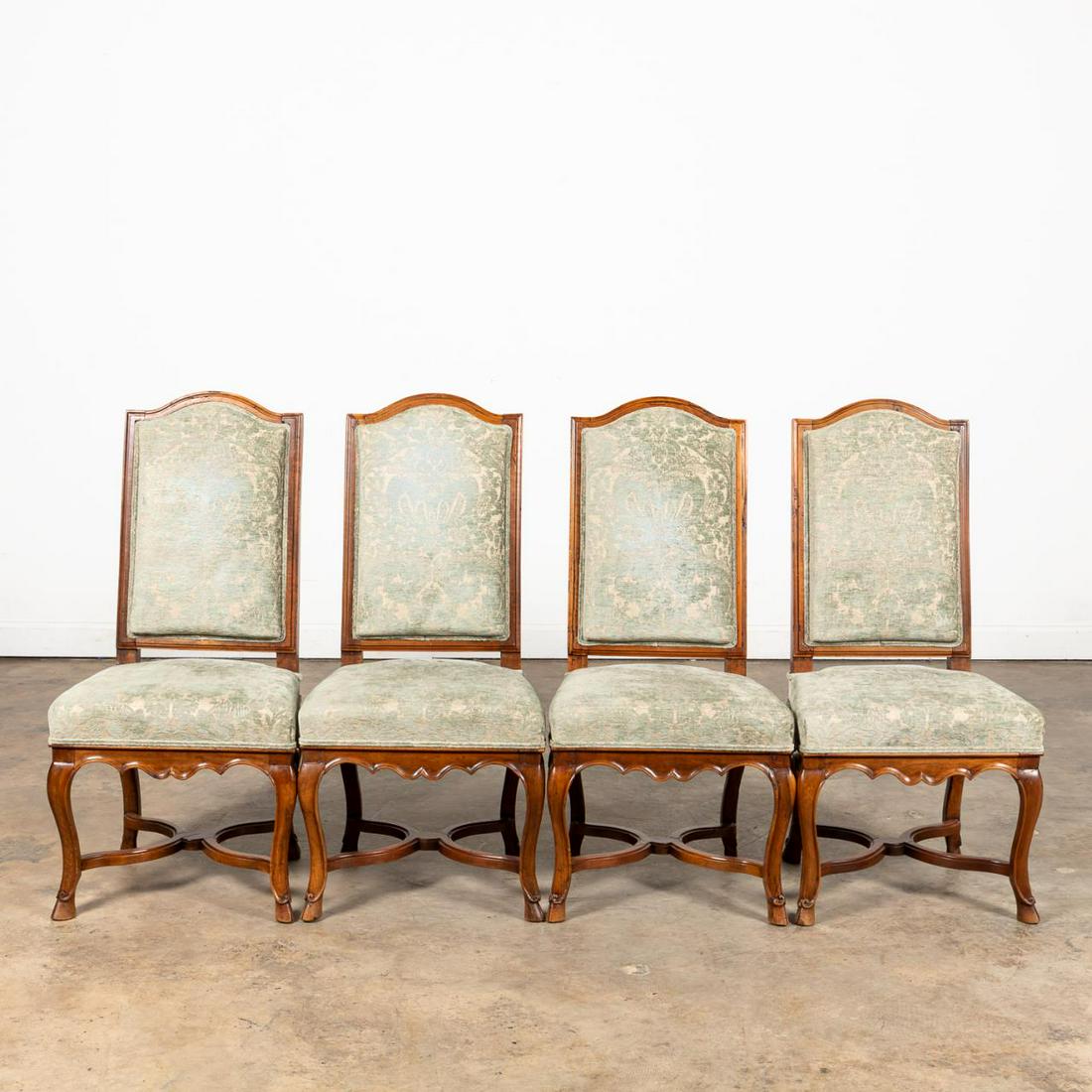 SET OF FOUR REGENCE-STYLE UPHOLSTERED SIDE CHAIRS: French, 19th century. Set of four carved walnut side chairs or chaises in the regence taste, having curved backs, pale blue cut chenille patterned upholstery, scalloped aprons, and rising on cabriole