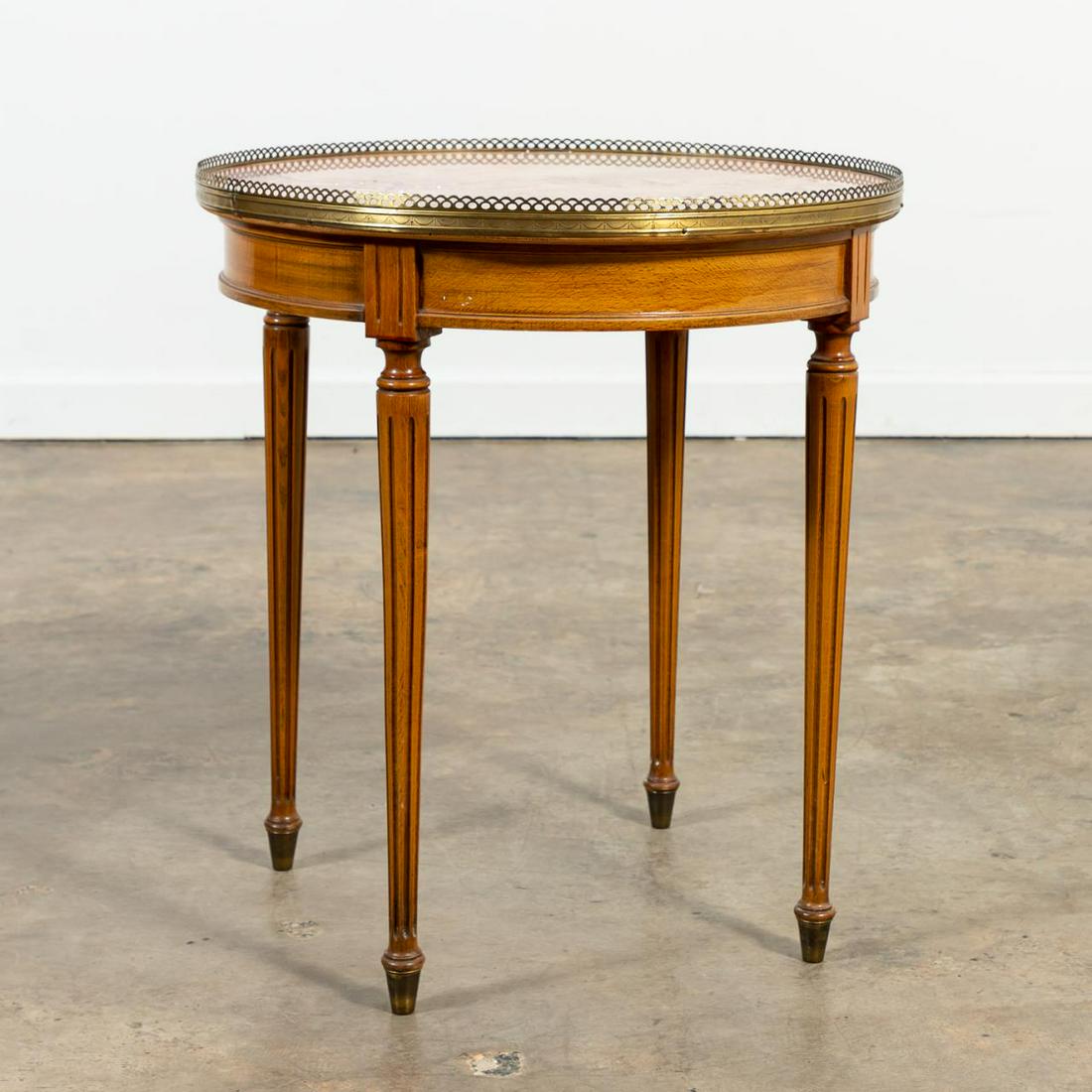 FRENCH FRUITWOOD BOUILLOTTE TABLE WITH PINK MARBLE: French, 20th century. Louis XVI-style round bouillotte table with pink and red marble, brass gallery,and turned fluted legs. "Made in France" to underside. Approx. h. 26.75", diam. 24".