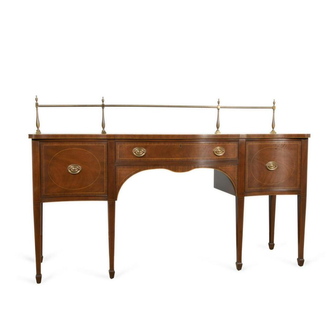 KITTINGER HEPPLEWHITE STYLE MAHOGANY SIDEBOARD: Kittinger Hepplewhite style mahogany veneer sideboard, D1002-1, having a brass gallery surmounting the serpentine top, above a conforming case with a center drawer flanked by wine drawers, all with ge
