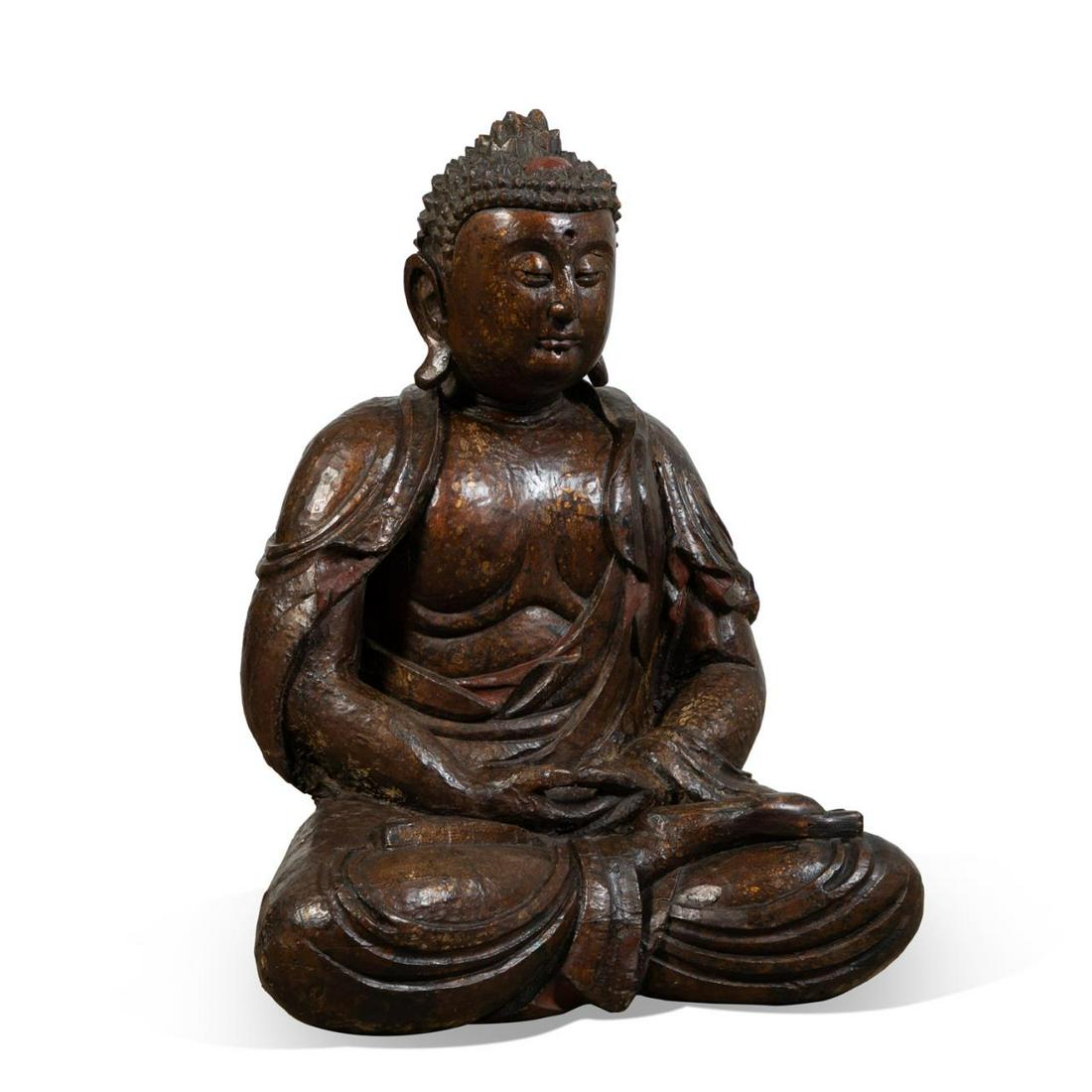 MONUMENTAL CARVED WOOD SEATED BUDDHA: Monumental seated Buddha, executed in carved wood with vestiges of gilt. depicting the Buddha with rosette hair, elongated earlobes, and seated in the Dhyana or meditation mudra, having no apparent ma