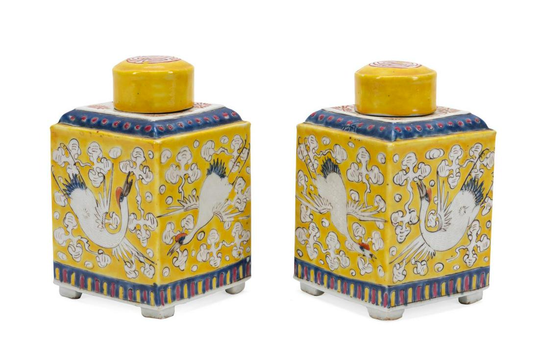 PAIR OF CHINESE YELLOW TEA CADDIES WITH CRANES: Pair of Chinese yellow tea caddies with cranes, of square section, each side decorated with a crane amidst auspicious cloud forms all on a yellow ground, terminating to a lappet style band, both havin
