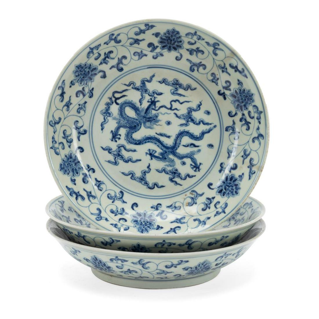 (3) CHINESE MING STYLE BLUE & WHITE DRAGON BOWLS: Three Chinese Ming style blue and white dragon bowls, each centering a writhing five clawed dragon amidst auspicious cloud forms framed by peony scrollwork, the exterior having conforming peony scroll