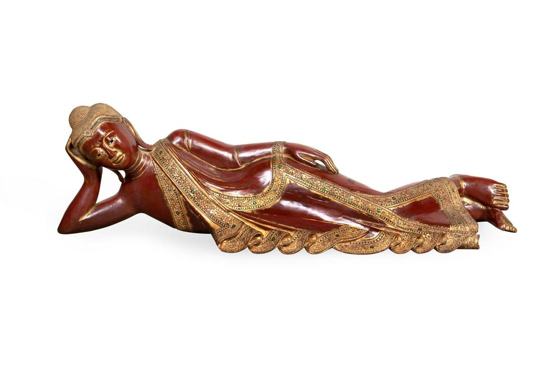 THAI RED CARVED WOOD RECLINING BUDDHA: Thai carved wood with polychrome pigment and parcel gilt reclining Buddha, depicted laying on his left side with his head cradled in one hand, representing tranquility and detachment from worldly worr