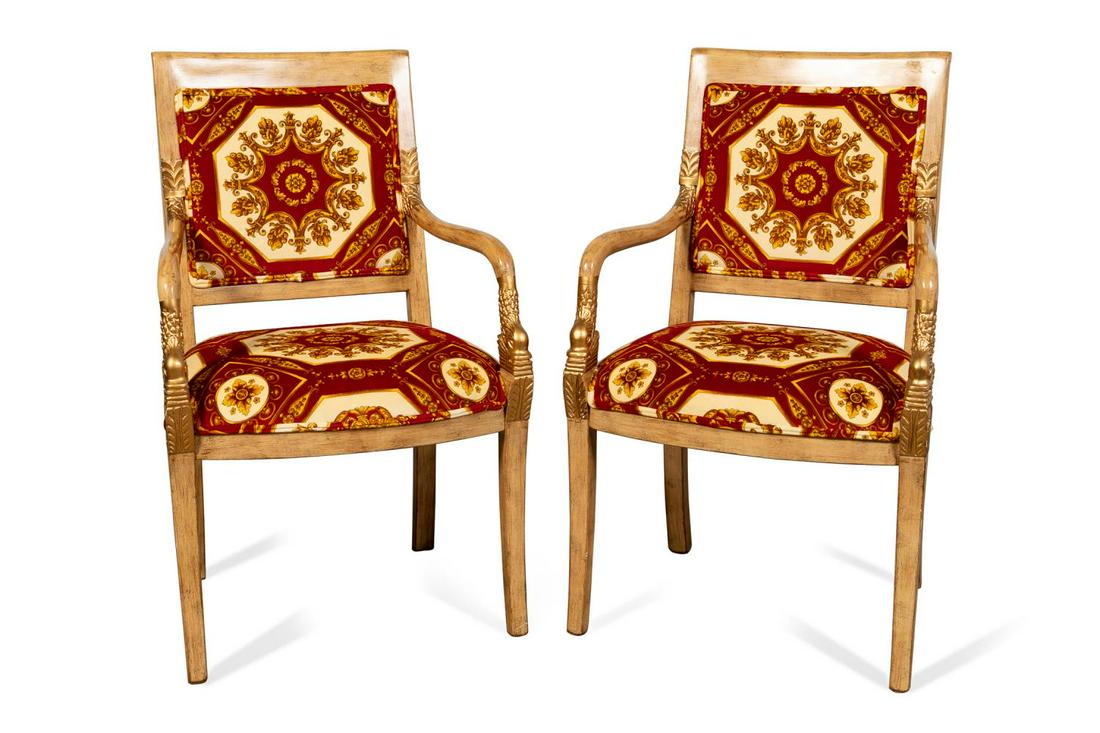 PAIR OF SIGLA VERSACE UPHOLSTERED ARMCHAIRS: Pair of Sigla Furniture parcel gilt armchairs in the Neoclassical taste, each having a distressed finish, dolphin head arm supports, likely Versace upholstery, and rising on curved legs, labels to und
