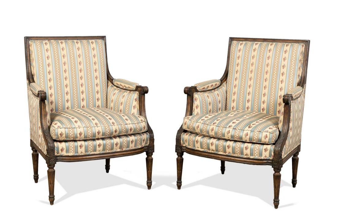 PAIR, LOUIS XVI STYLE FLORAL UPHOLSTERED BERGERES: Pair of walnut finished bergere enclosed armchairs in the Louis XVI taste, each having floral upholstery, square back, loose down seat cushion, and rising on fluted tapered legs with toupie feet, labe