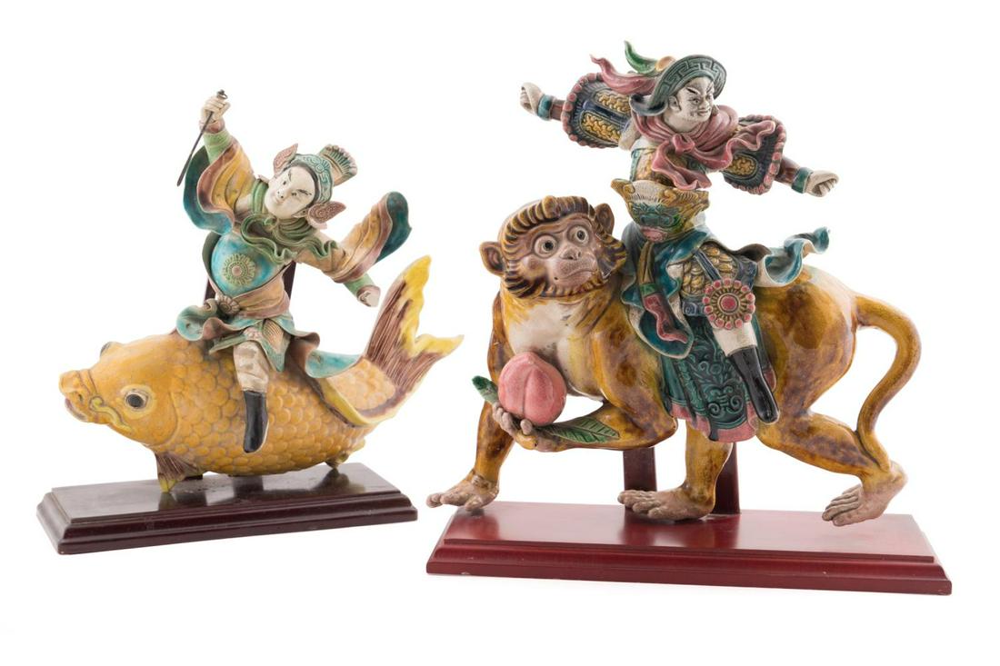 TWO CHINESE SANCAI GLAZED ROOF TILES ON STANDS: Group of two Chinese Sancai glazed earthenware roof tiles, modeled as a warrior on a monkey holding a peach and a warrior riding a carp, each having impressed marks, both resting on wooden stands. Pro