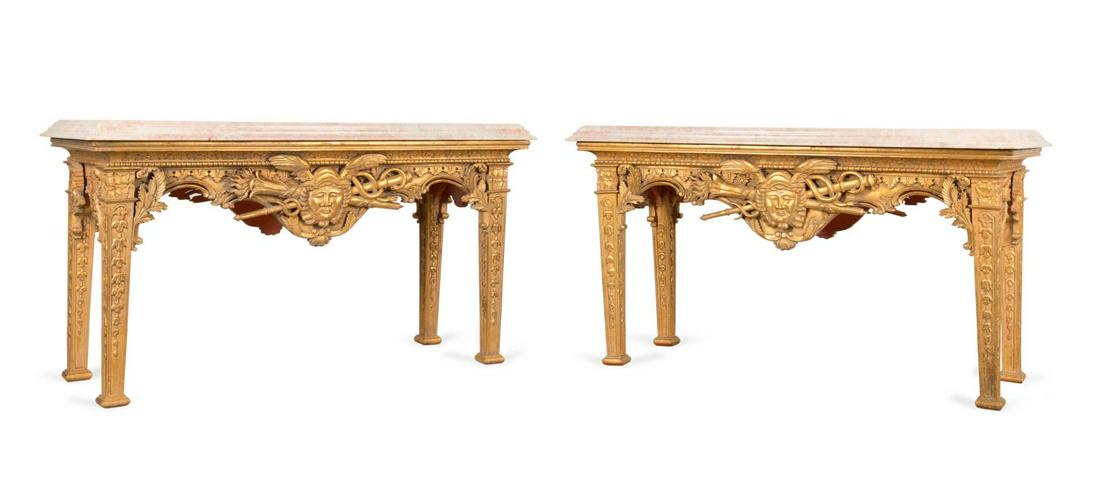 PAIR GEORGE II STYLE GILTWOOD CENTER TABLES: Pair of fully carved giltwood center tables in the Irish George II taste, each having a marble top, foliate carved cornice and frieze centering on masks of Hermes (Mercury) to the long sides, and risi