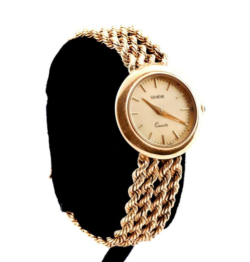 GENEVE 14K YELLOW GOLD LADIES WRIST WATCH: Geneve 14k yellow gold ladies wrist watch, featuring a round 27mm case with a gold face having stick markers and a gem set push/pull setting button, containing a quartz movement, flanked by a bracelet