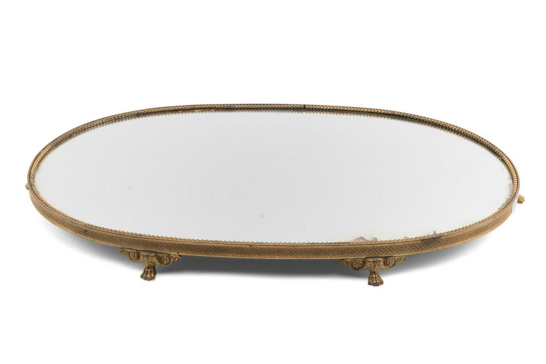 EMPIRE STYLE GILT BRONZE SURTOUT DE TABLE PLATEAU: French oval gilt bronze surtout de table plateau in the Empire taste, circa 1900, having a mirrored surface, beaded interior band, diapered edge, and rising on paw feet, apparently unmarked. Approxima