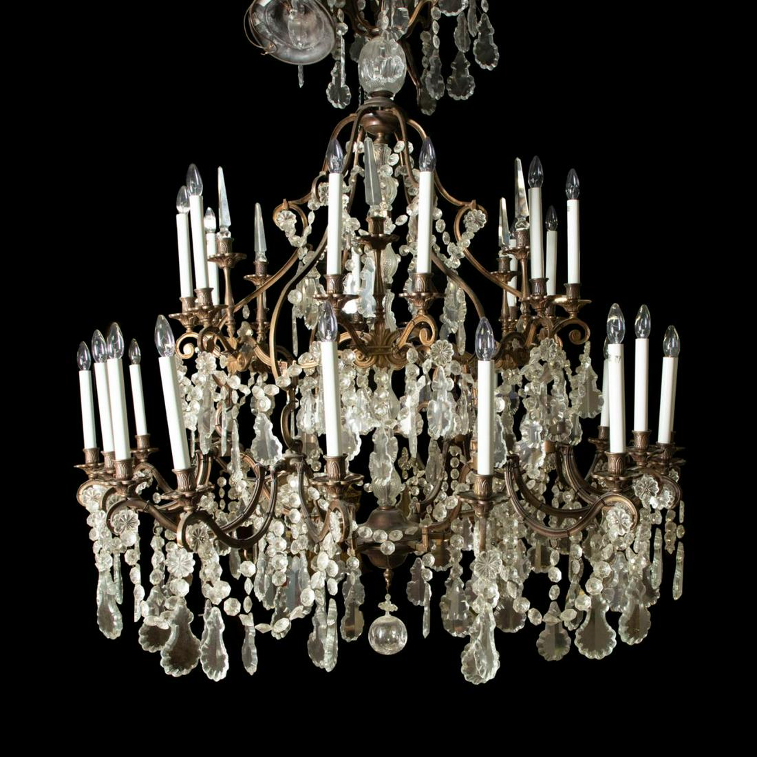 LARGE BAROQUE STYLE 30-LIGHT CRYSTAL CHANDELIER: Large Continental chandelier in the Louis XIV Baroque taste, having a scrolled bronze frame hung with faceted colorless crystal pendants and swags, 30 lights alternating with faceted spears, and termi