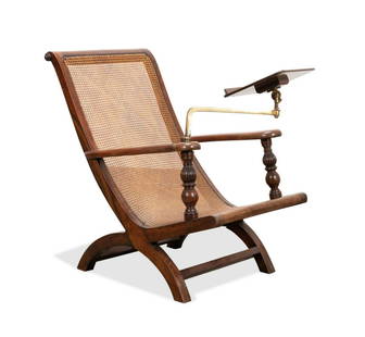 CANED WOOD PLANTATION CHAIR W/ BOOK REST: Tropical hardwood West Indies style campeche plantation chair, having a curule frame with caned panel, and adjustable book rest, having no apparent marks. Approximate dimensions: h. 39.5", w.