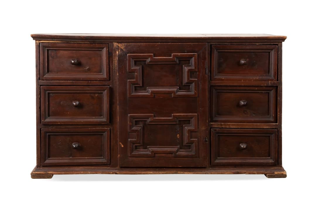 BAROQUE STYLE DARK STAINED PINE DRESSER: Spanish Baroque style dark stained pine dresser, 19th century, having a rectangular top with molded edge, over six drawers and carved panel cabinet door, rising on a plinth foot, having no apparent ma