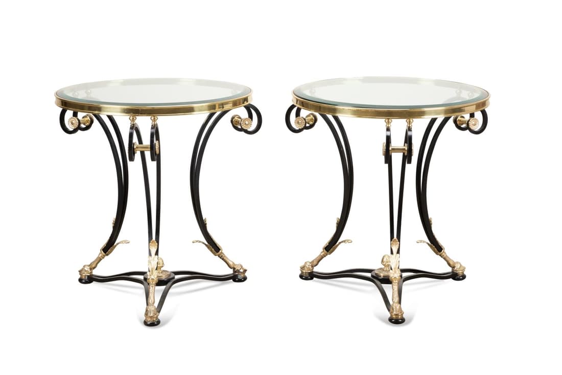 PAIR MAISON JANSEN STYLE GUERIDON SIDE TABLES: Pair of steel and brass gueridon side tables in the manner of Maison Jansen (French 1880-1989), with a circular glass top and rising on a tripartite base with paw feet, having no apparent marks. Appro