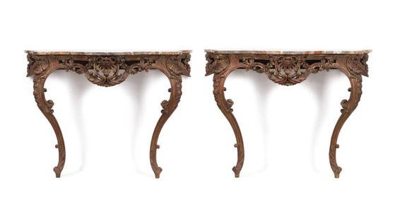 PAIR ITALIAN ROCOCO STYLE MARBLE TOP CONSOLES: Pair of Italian giltwood wall mounted console tables in the Rococo taste, each having a shaped marble top, rocaille foliate frame centering on a palmette, and rising on scrolled legs, apparently unmar