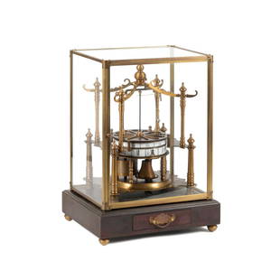 FLYING PENDULUM SKELETON CLOCK IN GLASS CASE: Flying ball pendulum brass skeleton clock, having enameled Arabic and Roman numerals, on dark stained wooden base, in glass case Approximate dimensions: h. 18.5", w. 13.25", d. 10.625".