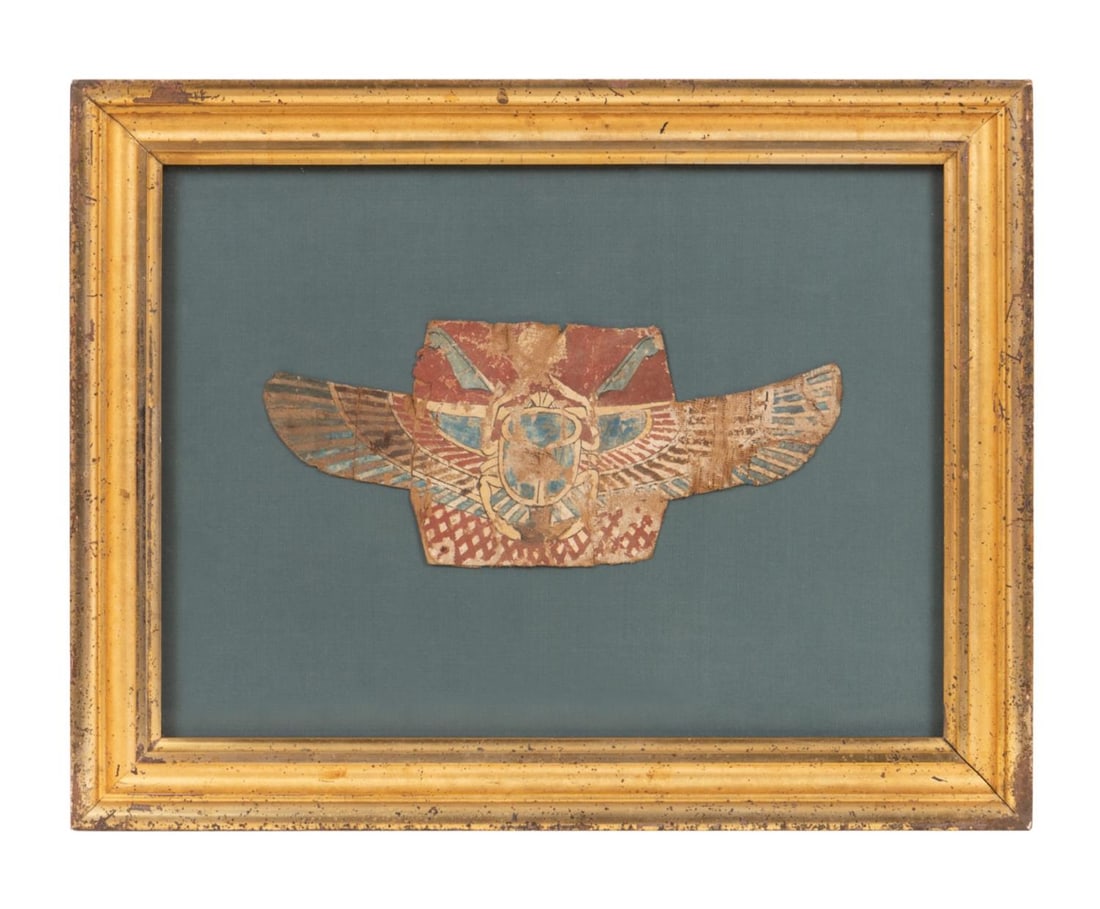 EGYPTIAN WINGED SCARAB CARTONNAGE FRAGMENT: Egyptian winged scarab cartonnage fragment in linen, gesso, and pigment, depicting a winged scarab on a brick red ground, the winged scarab de Noted rebirth and renewal, framed and under glass. Approx