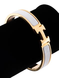 HERMES 'CLIC H' GOLD TONE & ENAMEL BRACELET: Hermes 'Clic H' white enamel and gold tone bangle bracelet, having a maker's mark, size GM, and manufacturers label. Approximate dimensions: interior diam 6.75", h. 2.25", w. 2.5", d. 0.5". Note: Ahle