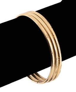 THREE 18K YELLOW GOLD BANGLE BRACELETS: Three 18k yellow gold bangle bracelets with patterned accents, each containing concealed tongue clasp assemblies, stamped for fineness. Approximate dimensions: h. 60mm, w. 65mm, d. 3.8mm, interior ban