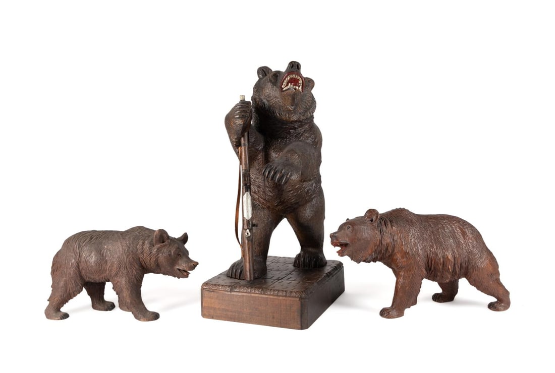 THREE BLACK FOREST STYLE CARVED WOOD BEARS: Three Black Forest style carved wood grizzly bears, the first carved standing upright, having glass eyes and an mouth open in a growl, holding a rifle, the whole resting on a rectangular plinth, toget
