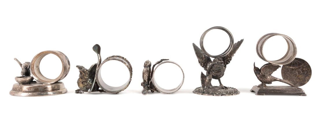 FIVE FIGURAL BIRD MOTIF SILVER PLATED NAPKIN RINGS: Five different late19th to early 20th century silver plated figural bird napkin rings including an owl, spring chicken with wish bone, chimney swift, bird with a nest and a large bird with a plant spr