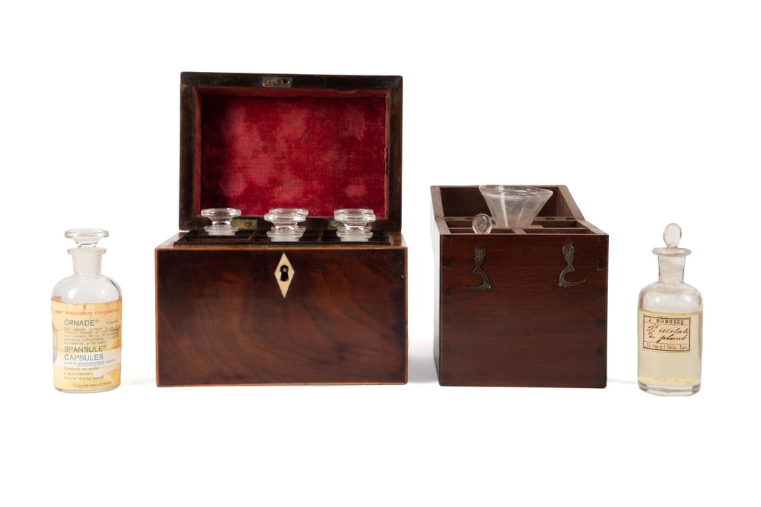 TWO WOODEN BOXES CONTAINING APOTHOCARY ITEMS: Two compartmentalized 19th century mahogany apothecary chests with glass bottles, the first chest has 3 compartments containing 2 glass bottles with raised tabbed stoppers,with faux stained dovetailin