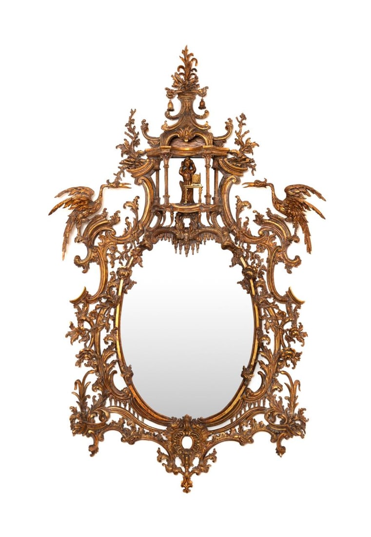 18TH/19TH CENTURY CHIPPENDALE OVAL GILTWOOD MIRROR: English, 18th/19th century. After a design by Thomas Chippendale (English, 1718-1779), large oval giltwood mirror in the George II or George III Chinese Chippendale taste, having a figure beneath a pa