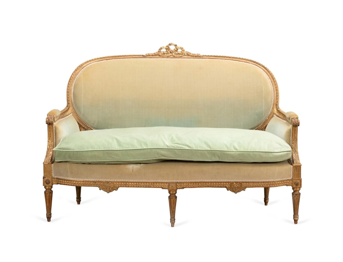 19TH C. LOUIS XVI STYLE GILTWOOD CANAPE BERGERE: French, 19th century. Giltwood canape bergere in the Louis XVI taste, having a ribbon tied crest on an oval back, enclosed arms, loose down filled seat cushion, and rising on stop fluted tapering legs