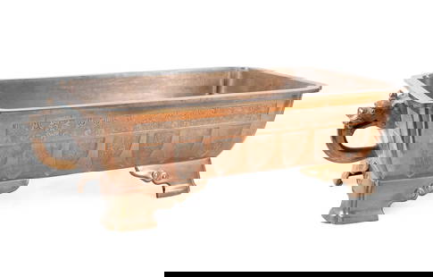 JAPANESE BRONZE SUIBAN BONSAI POT: Japanese, Meiji period. Bronze suiban pot for bonsai, of rectangular form, cast in high relief with a lappet border and geometric key-fret band, with twin dragon-head handles, raised on four bracket f