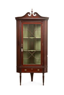 SHERATON REVIVAL MAHOGANY CORNER CABINET: American, last quarter 19th century. Centennial Sheraton Revival mahogany corner cabinet, having a scrolled broken pediment centering on an urn, single astragal glazed door, one drawer, and rising on