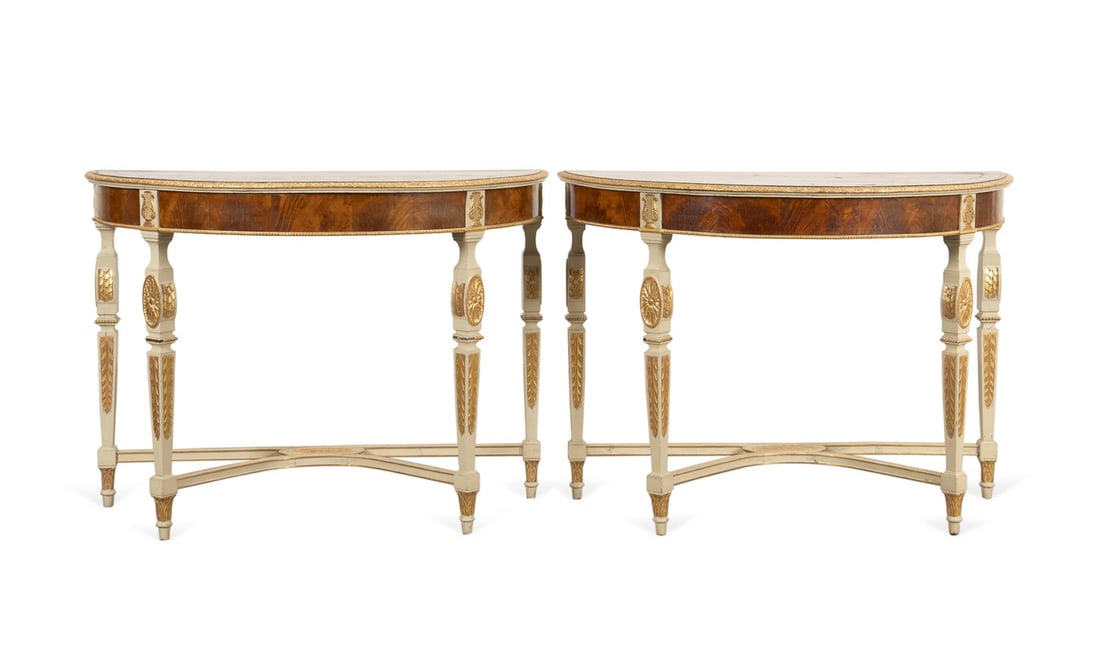 FRENCH LOUIS XVI STYLE DEMILUNE CONSOLE TABLES: French. Louis XVI style parcel-gilt and walnut veneer demilune console tables, having lyre, medallion, and acanthus leaf motif, and raised on tapered square legs with a curved stretcher. Provenance: P