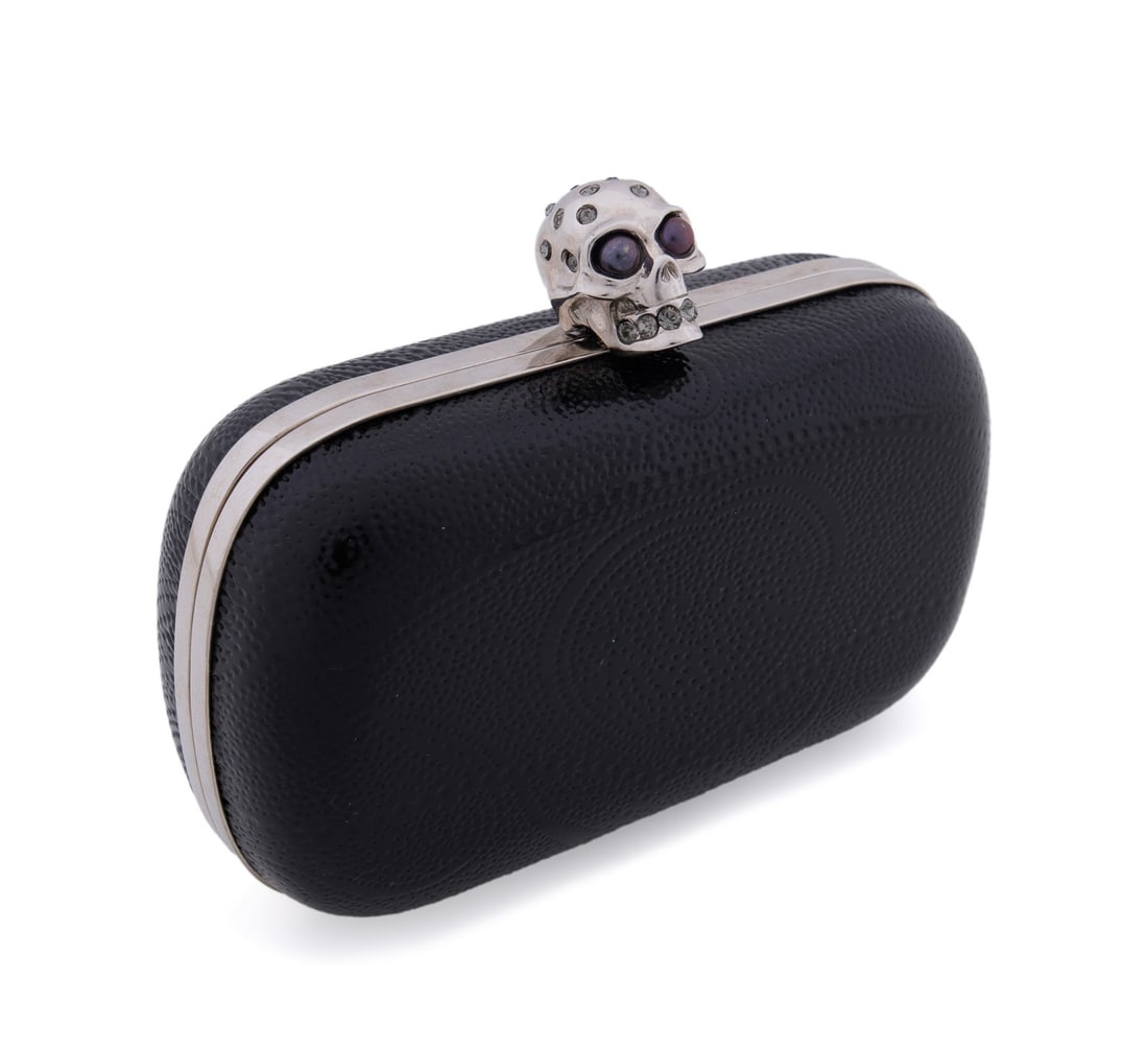 ALEXANDER MCQUEEN EMBOSSED LEATHER SKULL CLUTCH: Alexander McQueen (British, founded 1922). Dot embossed black patent leather skull box clutch with silver hardware, skull clasp with pearl and crystal embellishments. Accompanied by original tag. Appr