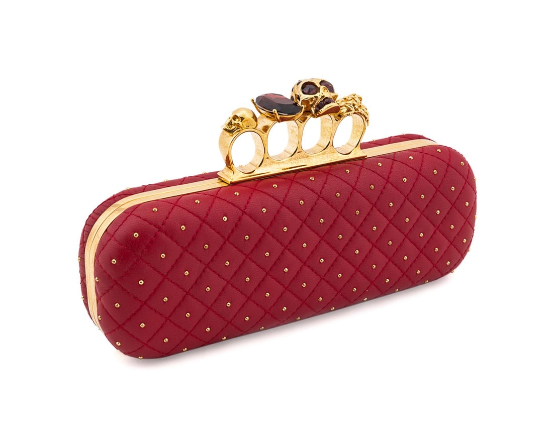 ALEXANDER MCQUEEN QUILTED STUD KNUCKLE BOX CLUTCH: Alexander McQueen (British, founded 1992). Red quilted leather knuckle box clutch with gold tone hardware, stud embellishments, and knuckle clasp with skull, floral, and jewel elements. Accompanied by