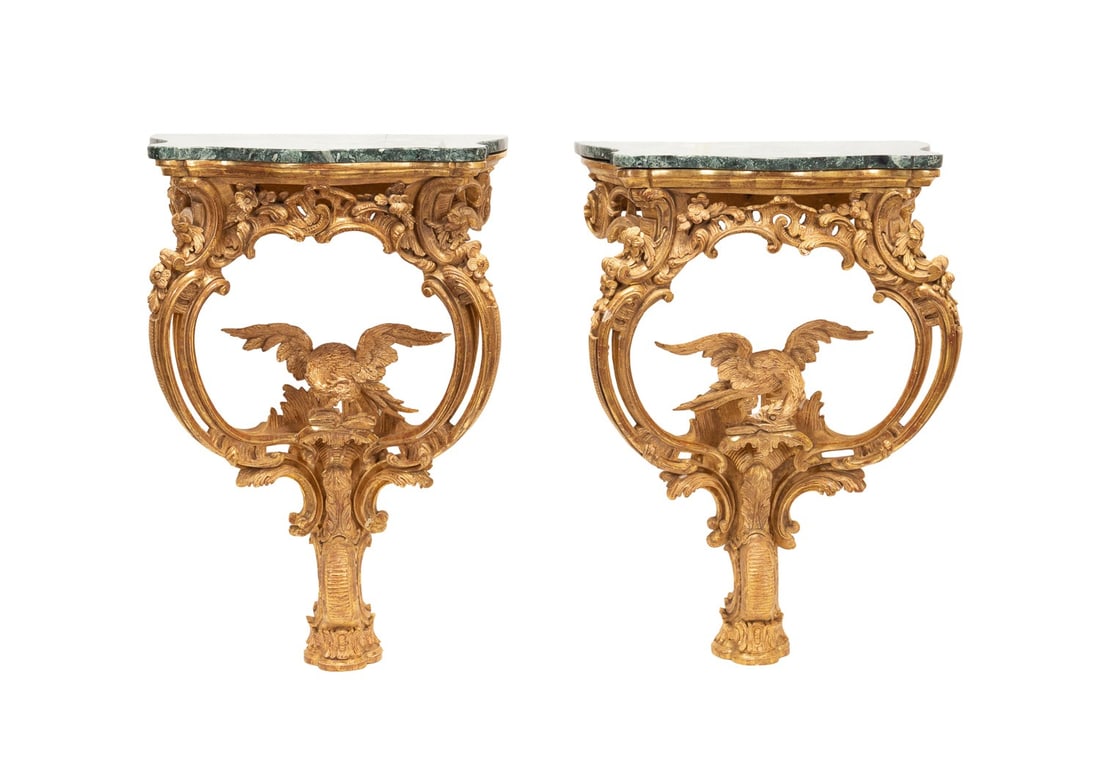 PAIR OF ROCOCO STYLE GILTWOOD CONSOLES: Continental, 19th / 20th century. Pair of giltwood wall mount console tables in the Rococo taste, having green marble overhanging tops, curving foliate rocaille centering on opposing eagles, and risin