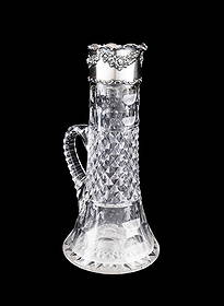 TOWLE STERLING SILVER MOUNTED CUT GLASS CLARET JUG: Towle Silversmiths (American, founded 1882), late 19th to early 20th century. American brilliant period cut glass claret jug, having a floral repousse sterling silver collar, the collar appropriately