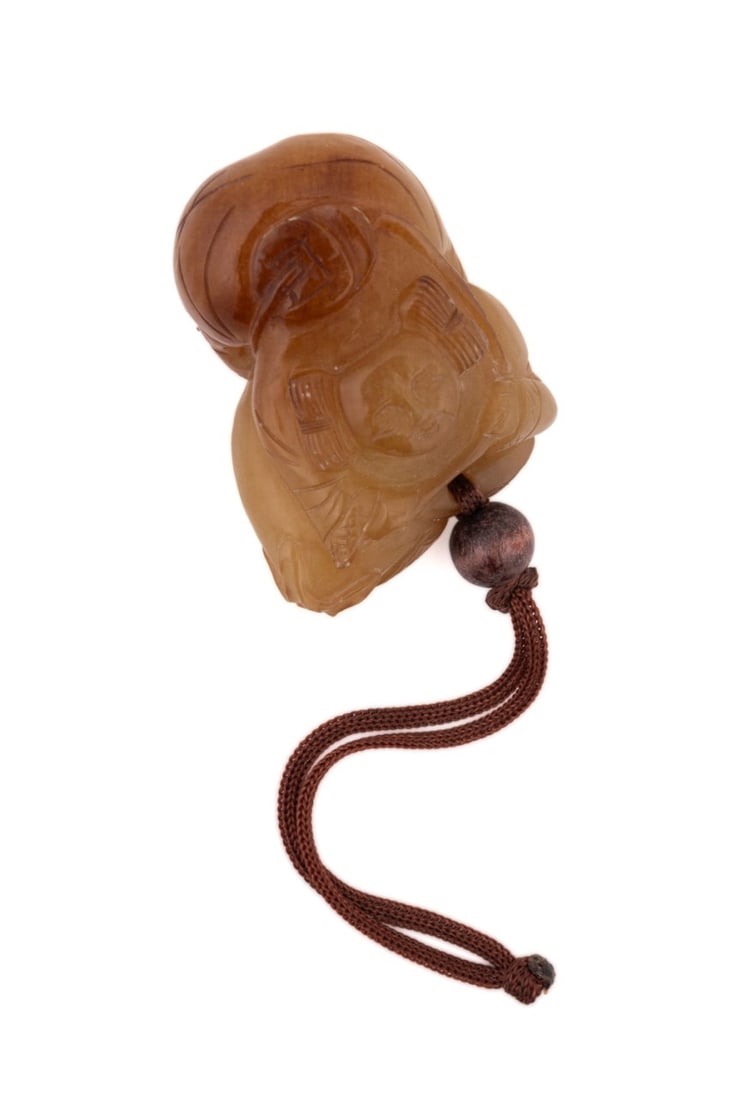 NATURAL JADE CARVED PENDANT: 20th century. Green and brown carved pendant of a young female with bead and silk cord. Provenance: The Estate of Jain Ming James Wu, Huntsville, AL. Approximate dimensions: h. 1", w. 2".