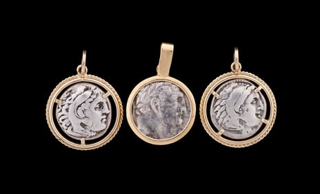 THREE ANCIENT SILVER COINS SET INTO GOLD BEZELS