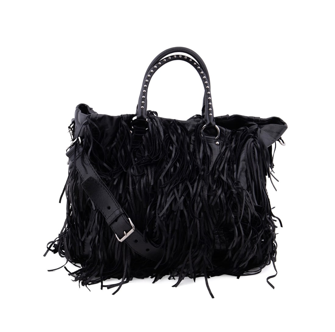 PRADA BLACK VITELLO LEATHER FRINGE TOTE WITH STUDS: Prada (Italian, founded 1913). Black vitello shine leather fringe tote with silver toned hardware and studs on straps. Accompanied by dust bag, removable crossbody strap, care pamphlet, and authentici