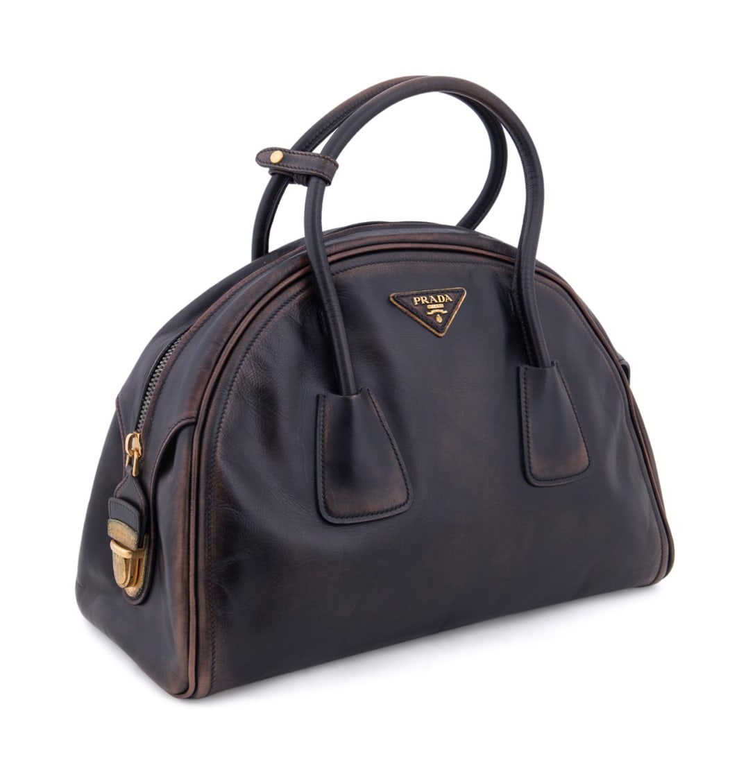 PRADA BROWN DISTRESSED VITELLO LEATHER BOWLER BAG: Prada (Italian, founded 1913). Vintage inspired distressed vitello leather bowling bag with two top handles, gold toned hardware, and leather lining. Accompanied by dust bag, care pamphlet, and authen