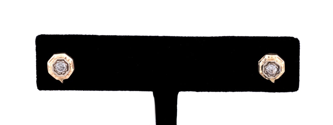 DIAMOND & 14K WHITE GOLD STUD EARRINGS: Pair of diamond stud earrings, each earring with a round cut diamond (approximately 0.12 carats) prong set in white gold within an engraved yellow gold octagonal border. Set in 14k gold. Unmarked but