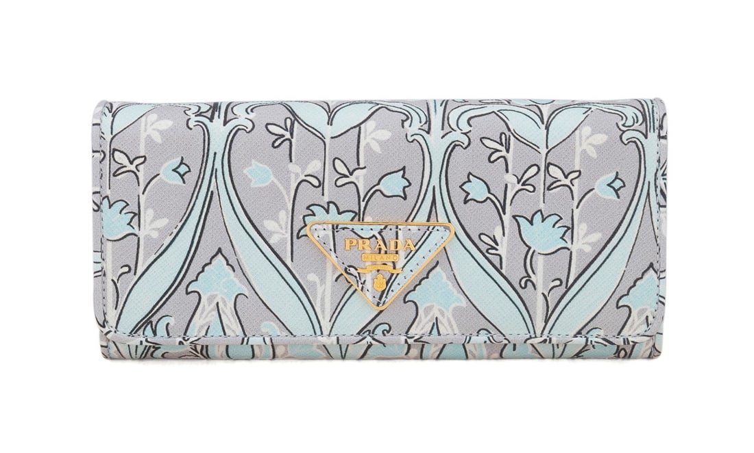PRADA SAFFIANO LEATHER FLORAL PRINT FLAP WALLET: Prada (Italian, founded 1913). Anice blue, grey, white, and black floral printed saffiano leather wallet with gold hardware, snap front closure, and multiple interior pockets and slots. Accompanied by
