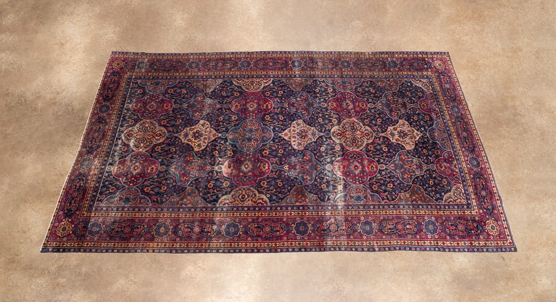 ROOM SIZED ANTIQUE PERSIAN KHORASAN RUG: Persian, early 20th century. Khorasan rug decorated in tones of red, cochineal purple, blue, brown, and bone, apparently unsigned. The rug has been reduced in size at one end and is offered together w