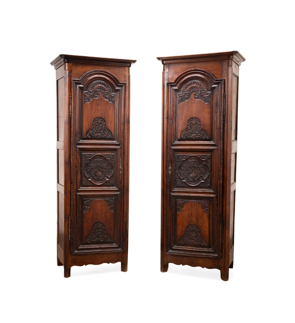 19TH C. PAIR OF FRENCH BONNETIERE CABINETS: French, 19th century. Pair of Louis XV Provincial style bonnetiere cabinets, with shaped cornices, carved panel doors having acanthine and floral motif, and raised on square legs, apparently unmarked.