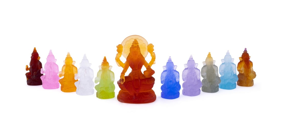 DAUM, GROUP OF ELEVEN LAKSHMI AND GANESHA FIGURINE: Daum (French, founded 1878). Limited edition amber "Lakshmi" pate de verre seated figurine with acid-etched signature "Daum France" and numbered "057/888" to the back of the figurine. Variously colore